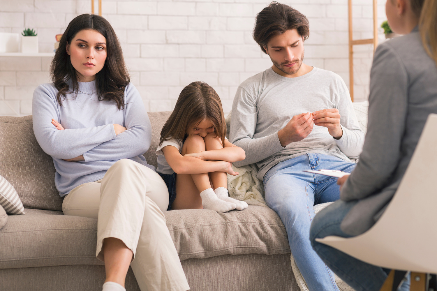 Family Counselling Concept. Unhappy Man And Woman And Their Upset Little Daughter Sitting At Psychologist's Office, Having Therapy