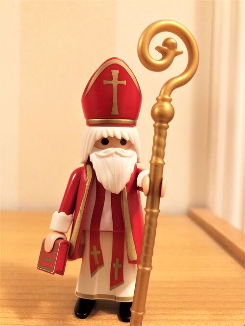 Nikolaus-Figur mit Bischofsmütze, Stab und Buch vor hellem Hintergrund