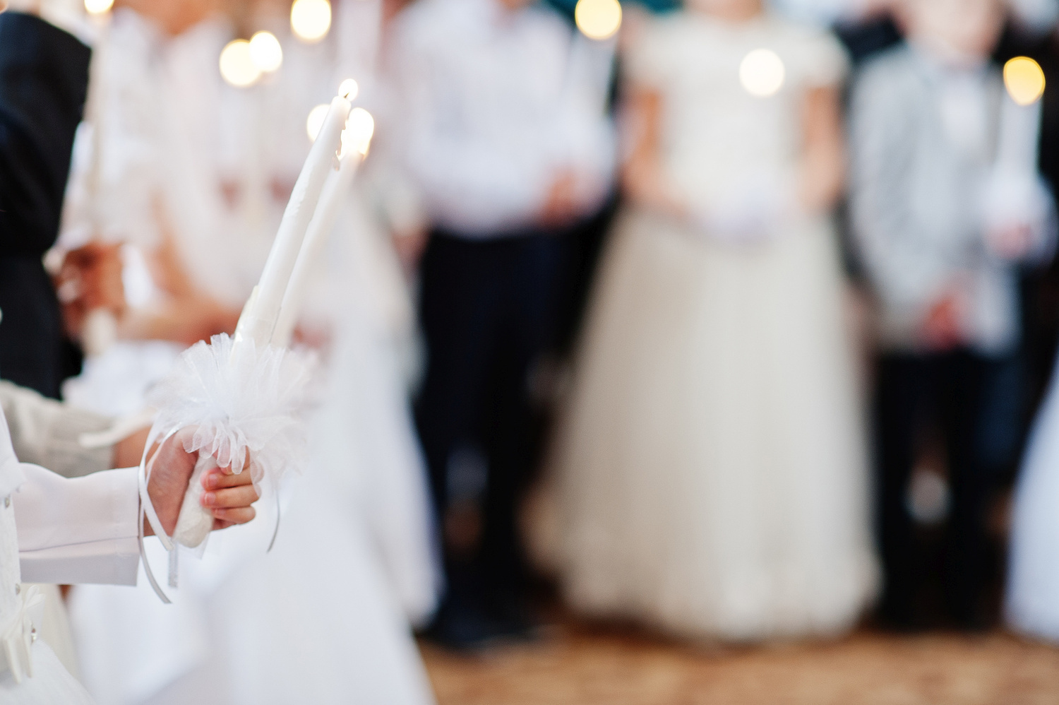Young girl in white hold candle in hand at first holy communion.